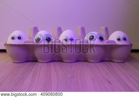 Eggs With Eyes. Backlit Background. A Box With White Eggs.