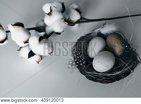 Stylized Happy Easter card,  closeup  with beige and white eggs in nest , polka dot  and white feathers, straw and cotton flowers.