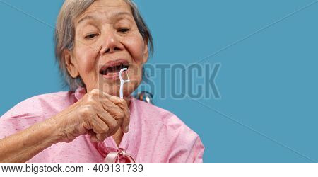 Caregiver Take Care Asian Elderly Woman While Using Dental Fross Stick.