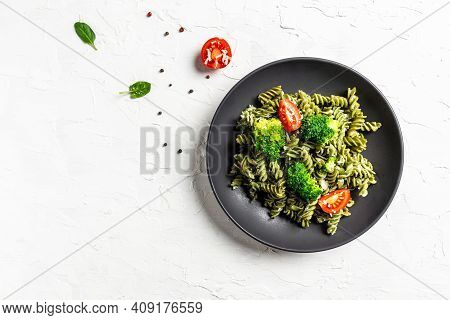 Vegan Green Pasta With Broccoli, Avocado Sauce, Spinach Leaves And Cherry Tomatoes On Liht Backgroun
