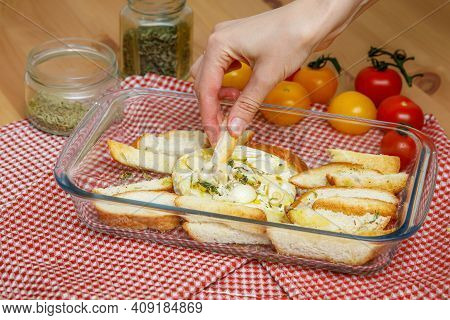Camamber Baked With Garlic And Spices. Hand Dunking Crispbread In Melted Cheese