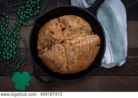 Photograph Of Irish Soda Bread Baked In A Cast Iron Skillet With Shamrock Beads For Saint Patrick's 