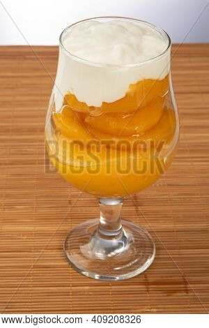 Peaches In Syrup Placed In Bowl Covered With Sour Cream On Wooden Mat, Gray Gradient Background, Sel