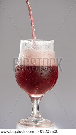 Red Beer Filling A Glass Of Red Beer, Gray Gradient Background, Selective Focus.