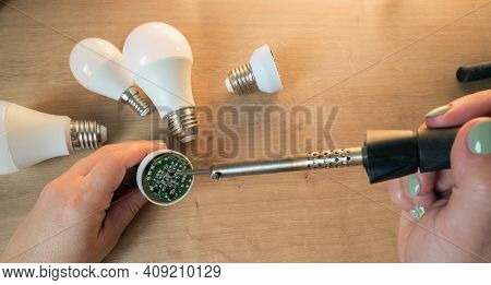 Woman Repairing A Led Lamp With A Soldering Iron