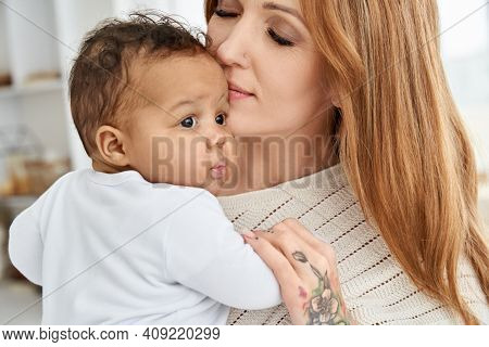 Loving Young Caucasian Mother Hugging Cute Infant African American Baby Daughter Expressing Single P