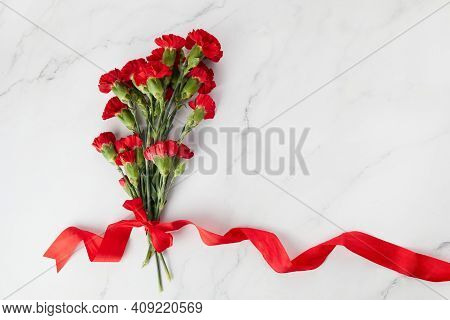 Beaytiful Carnation Flowers With Red Ribbon On Marble Background. Top View