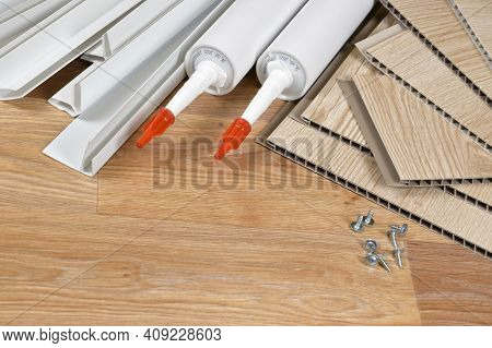 Set Of Items For Pvc Ceiling Indoor Works. Assembly Adhesive Bottles And Pvc Panels With Plastic Cor