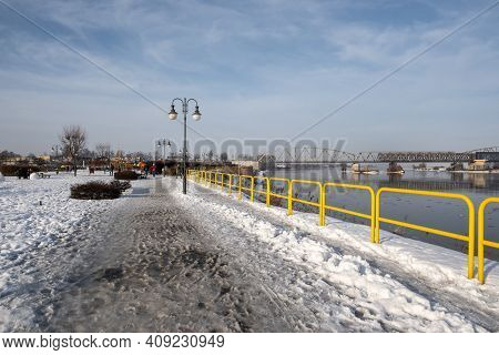 Tczew, Poland - February 21, 2021: Vistula Riverbank Promenade In Tczew. The Historic Bridge In Back