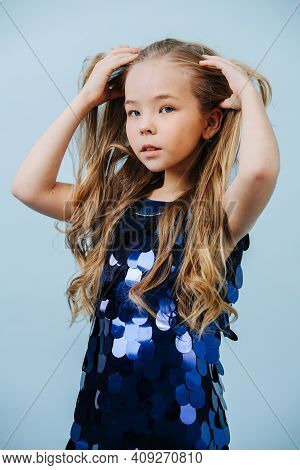 Adorable Girl In A Glittering Blue Scaled Dress Taking Care Of Her Messy Hair