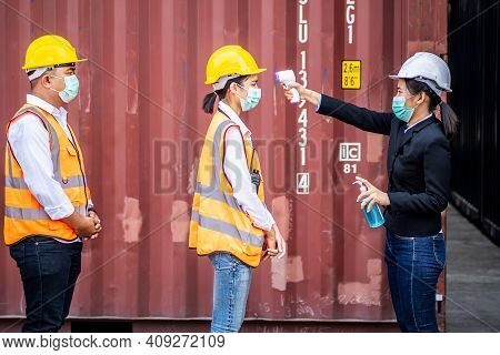 Female Foreman Wearing A Mask Measures The Temperature For A Worker In A Safety Suit. They Stood And