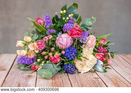 Close Up View Of A Beautiful Bouquet Of Mixed Coloful Flowers On Wooden Table. The Concept Of A Flow
