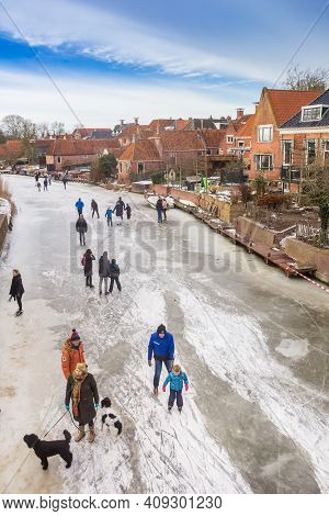 Winsum, Netherlands - February 14, 2021: People Walking Their Dogs On The Frozen River In Winsum, Ne