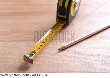 Self Retracting Metal Measuring Tape And Pencil On Wooden Table, Closeup
