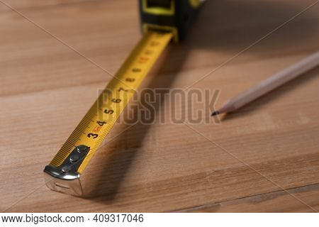 Self Retracting Metal Measuring Tape And Pencil On Wooden Table, Closeup
