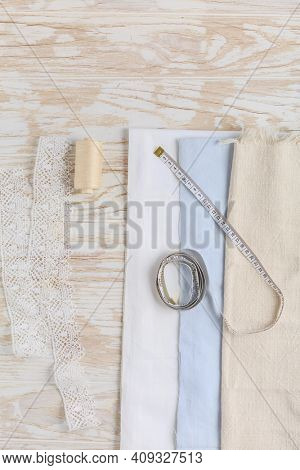 Sewing tools and supplies - fabric and centimeter with thread on wooden table.