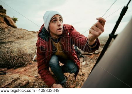 Caucasian Male Concentrating Puling Ropes To Tie Tent Camping On Top Of Mountain