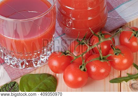 Half Full Glass With Tomato Juice With Pulp Stands On A Table Next To Tomatoes On A Branch Close-up 