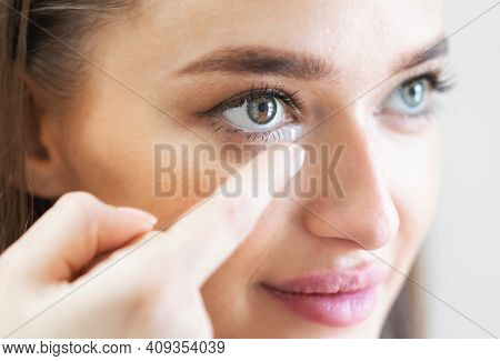 Ophthalmology And Eyecare. Closeup Portrait Of Young Woman Applying Eye Lens. Smiling Female Using A