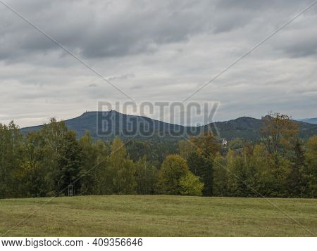 Meadow With Autumn Colorful Forest, Trees And Hills And Hvozd Or Hochwald Lookout Tower, Moody Sky. 