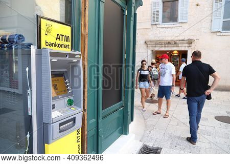 Split, Croatia - July 20, 2019: Tourists Walk By Atm Banking Machine In Split. Croatia Had 18.4 Mill