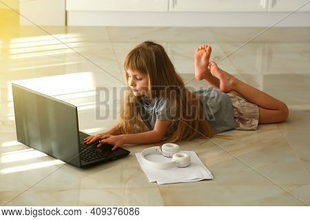 One Little Girl Lying At The Floor And Using Laptop.