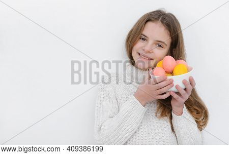 A10 Year Old European Girl With Pink And Yellow Easter Eggs In Her Hands, Wearing A White Sweater Ag