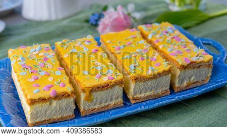 Four Tompouce Cakes With Whipped Cream And Yellow Icing Served In Sunny Spring Garden