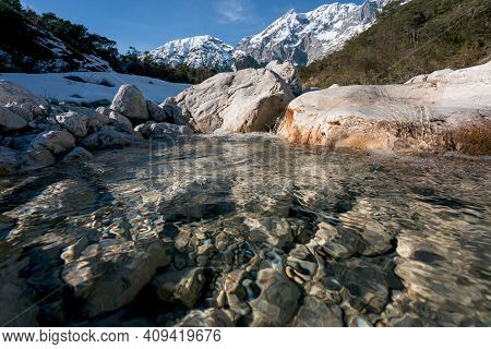 Wild Clear Mountain River Flowing Over Rocks Through Evergreen Forest With Last Snow, Mieminger Plat