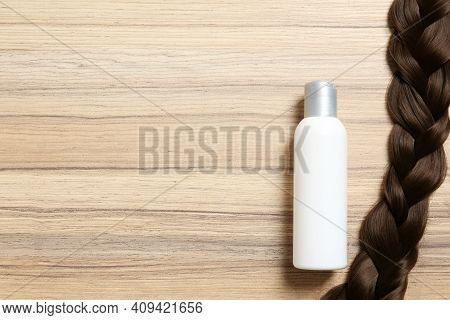 Shampoo Bottle And Braid On Wooden Background, Flat Lay. Space For Text