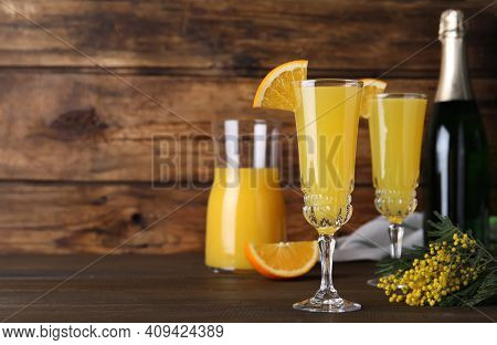 Glasses Of Mimosa Cocktail With Garnish On Wooden Table. Space For Text