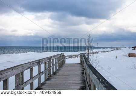 An Old, Wooden Bridge Crosses A Section Of Frozen Georgian Bay Waterfront In Collingwood, Ontario. T