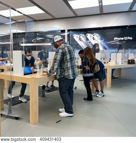 Apple Employees Waiting On Customers With Plexiglass Sheilds Between While Wearing Face Masks Due To