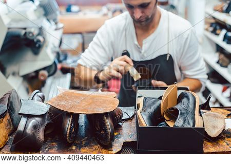 Shoemaker putting glue on sole of a shoe to fix