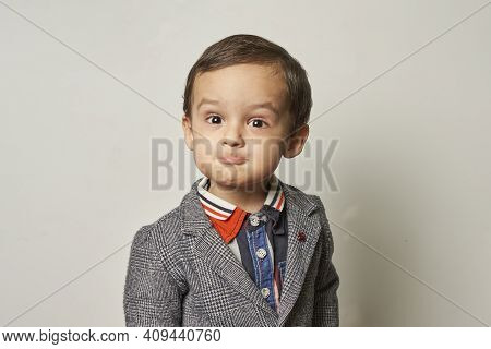 Funny Portrait Of A 2-years-old Boy In A Handmade Elegant Suit. A Kid Boy Making A Funny Foolish Fac