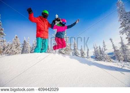 Couple Happy Lover Having Jump Fun In Winter Snow Forest. Snowbarders And Skiers Team Friendship