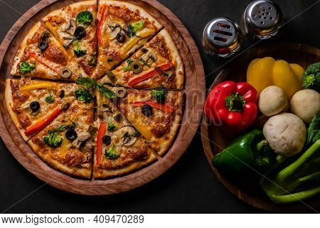 Top View Of Picante Pizza With Vegetables Kept On Right Side On Black Surface