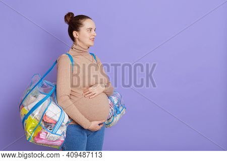 Portrait Of Young Pregnant Woman Hugging Big Belly And Looking Away, Posing Isolated Over Lilac Back