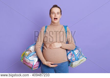 Young Female Wearing Casual Clothing Posing Isolated Over Lilac Wall With Widely Opened Mouth, Looks