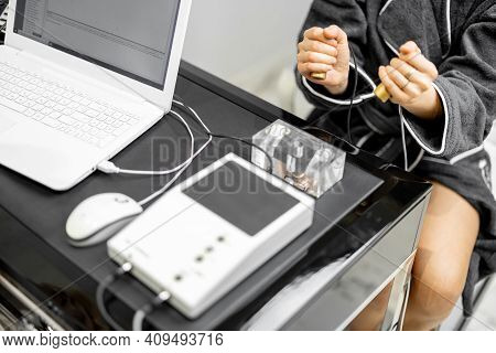 Woman Takes Hold Of The Brass Handpieces Of Bioenergetic Testing Device