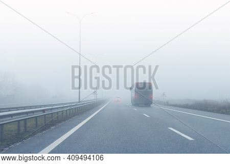 Coach Bus On Almost Empty Blue Foggy Misty Rainy Highway Intercity Road With Low Poor Visibility On 