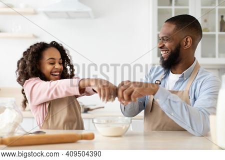 Cooking With Daddy Is Fun. Happy African American Father And His Cute Daughter Making Dough At Kitch