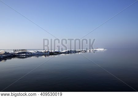 Icy Road To The Lighthouse On Mangalsala Pier In Baltic Sea Located At Riga Sea Port, Latvia, Europe