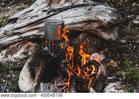 Kettle Hanging Over Fire. Cooking Food At Fire In Wild. Beautiful Big Log Burns In Bonfire Close-up.
