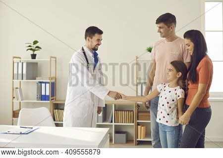 Happy Mom, Dad And Child Visiting Hospital And Getting Acquainted With New Family Doctor