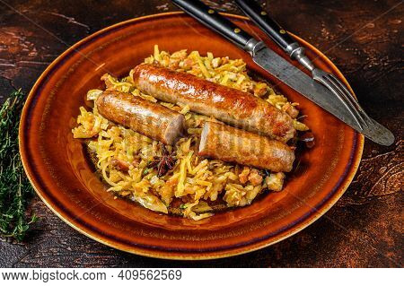 Bigos Stewed Cabbage With Mushrooms And Meat Sausages On A Plate. Dark Background. Top View