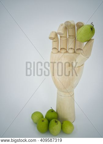 Indian Jujube Fruit Or Ziziphus Mauritiana Or Buah Bidara In A Rattan Bowl With A Wooden Hand Model.
