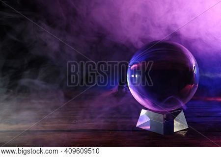 Crystal Ball On Table And Smoke Against Dark Background, Space For Text. Predictions Of Future