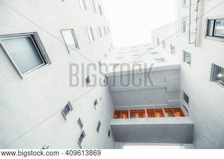 A Wide-angle View From The Bottom Of A White Modern Residential House With An Illuminated By An Oran