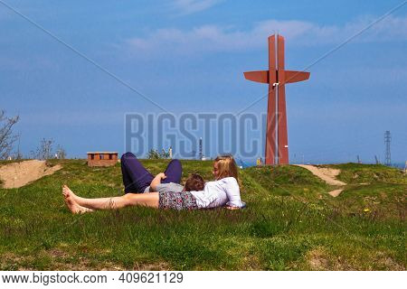 Gdansk, Poland - May 14, 2017: Unknown Young Couple Resting On The Grass Near Millennium Cross Monum